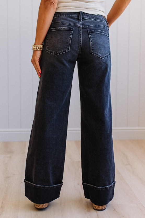 Person wearing dark blue wide-leg jeans with a white background