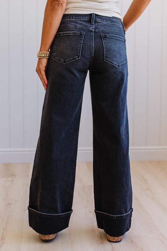 Person wearing dark blue wide-leg jeans with a white background