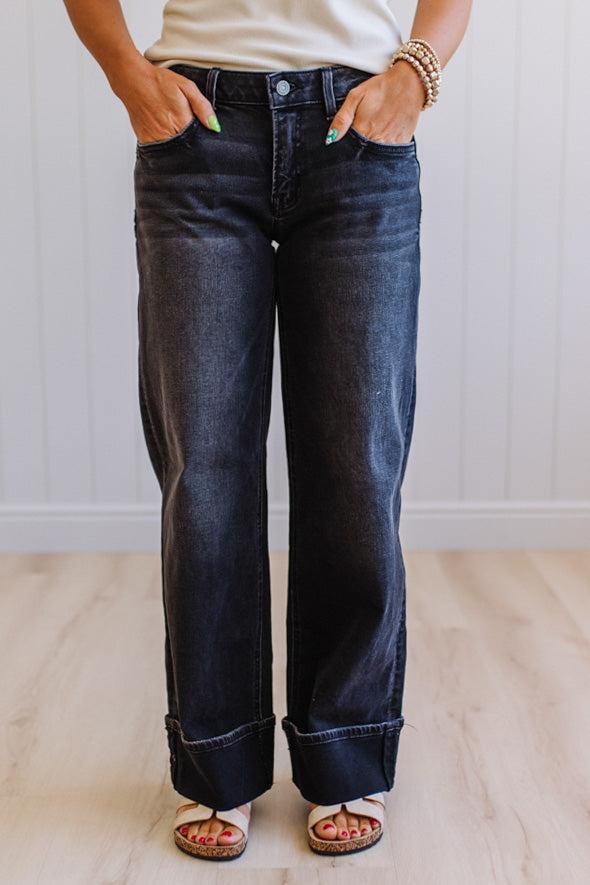 Person wearing dark blue jeans with a neutral background
