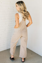 Blonde woman wearing solid colored overalls with cropped wide leg and knotted strap.
