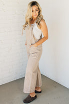 Blonde woman wearing solid colored overalls with cropped wide leg and knotted strap.