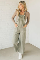 Blonde woman wearing solid colored overalls with cropped wide leg and knotted strap.