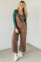 Blonde woman wearing solid colored overalls with cropped wide leg and knotted strap.