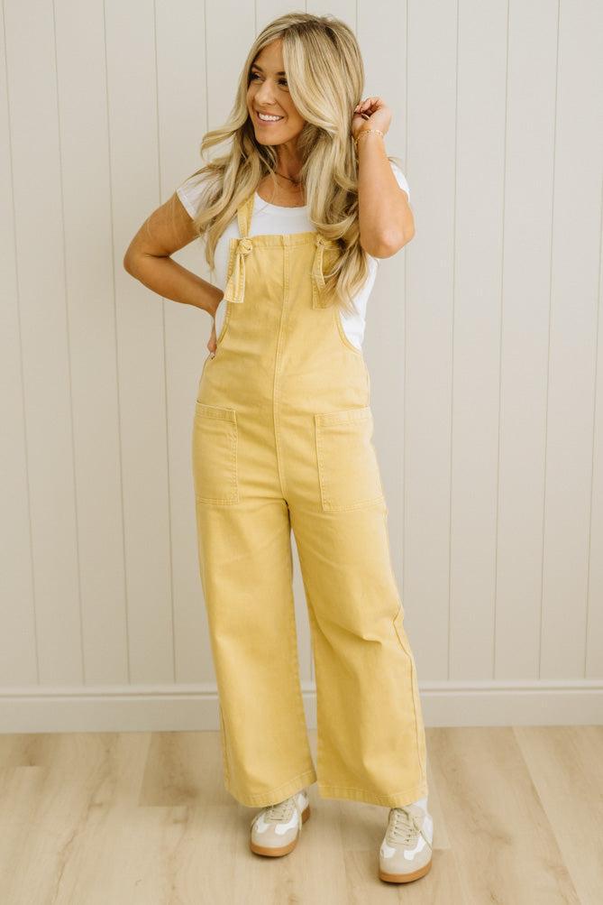 Woman wearing a yellow jumpsuit with a white background