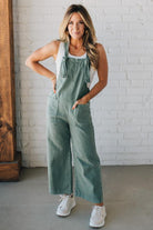 Blonde woman wearing solid colored overalls with cropped wide leg and knotted strap.