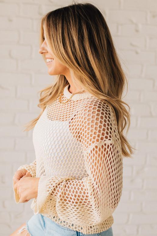 BLONDE WOMAN WEARING A CREAM LONG SLEEVE OPEN KNIT LOOSE FIT COVER UP TOP.