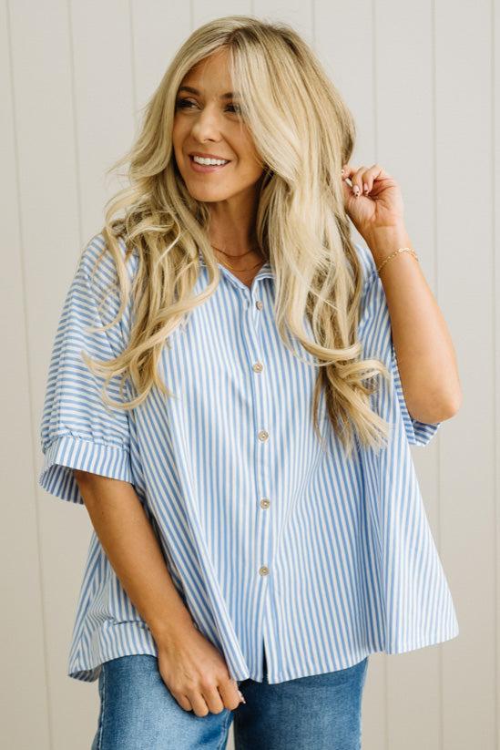 Woman wearing a blue and white striped shirt against a wooden panel background