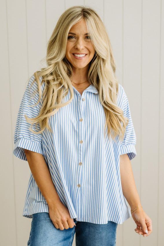 Woman wearing a blue and white striped shirt against a beige wall