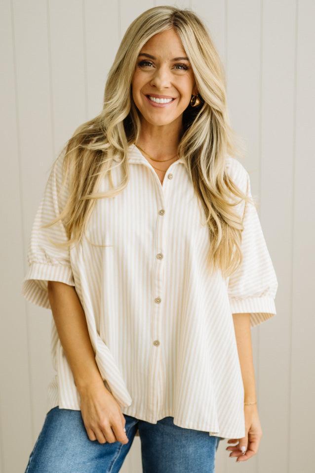 Woman wearing a white button-up shirt and blue jeans against a neutral background