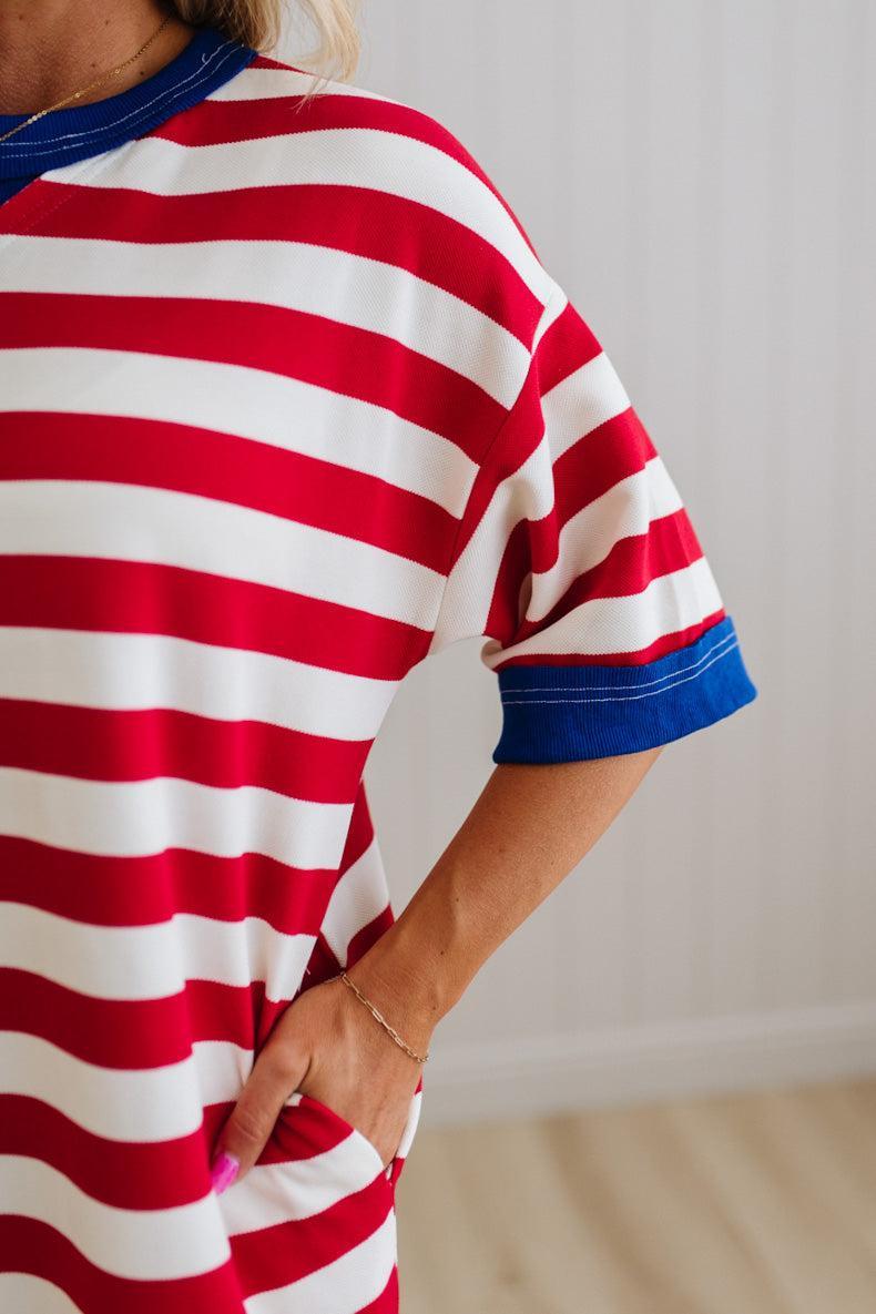 Red and white striped shirt with blue trim worn by a person against a neutral background