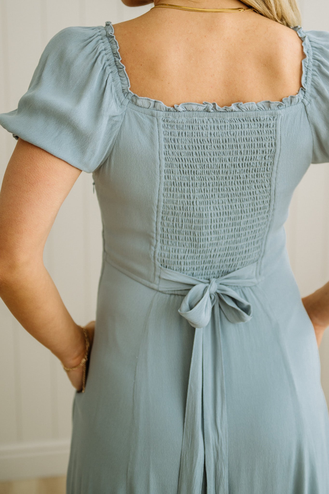Light blue dress with smocked bodice and tied waist on a neutral background