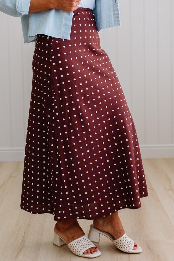 Person wearing a burgundy skirt with white polka dots indoors.