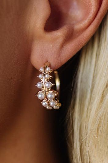 Gold earring with pearls worn on an ear