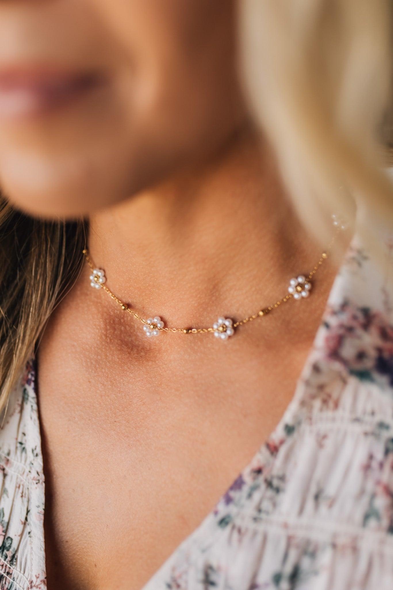 Close-up of a delicate necklace with floral designs on a blurred background