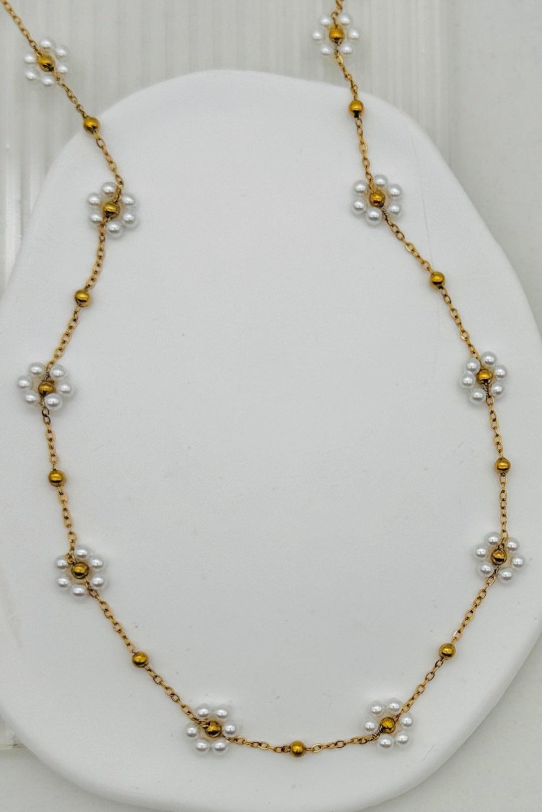 Necklace with gold and pearl beads on a white stand
