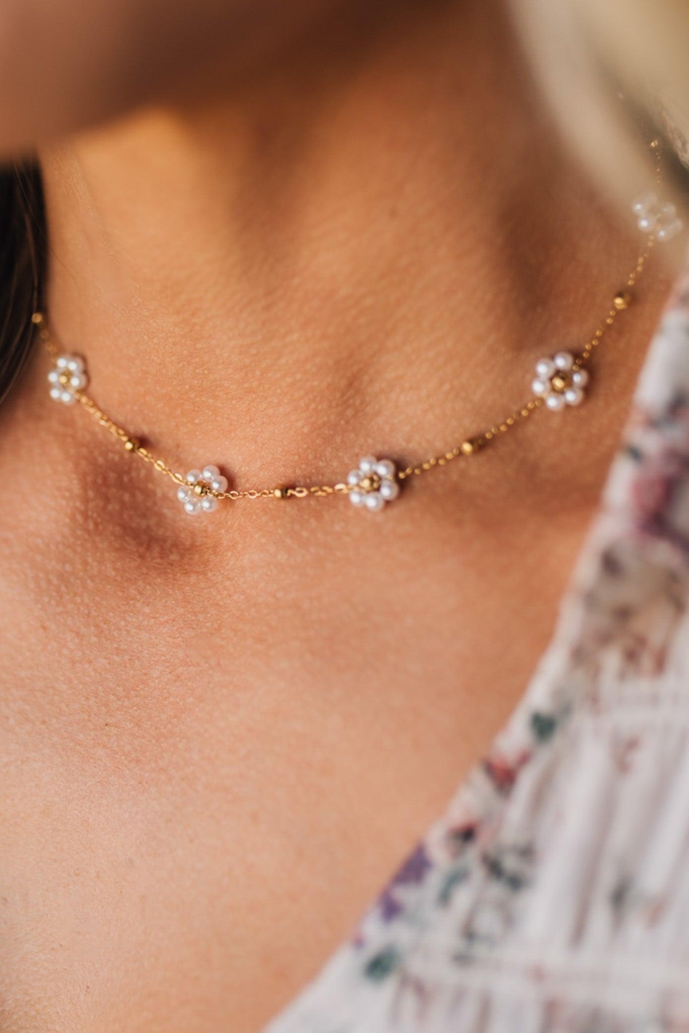 Close-up of a delicate gold necklace with floral pendants on a person's neck.