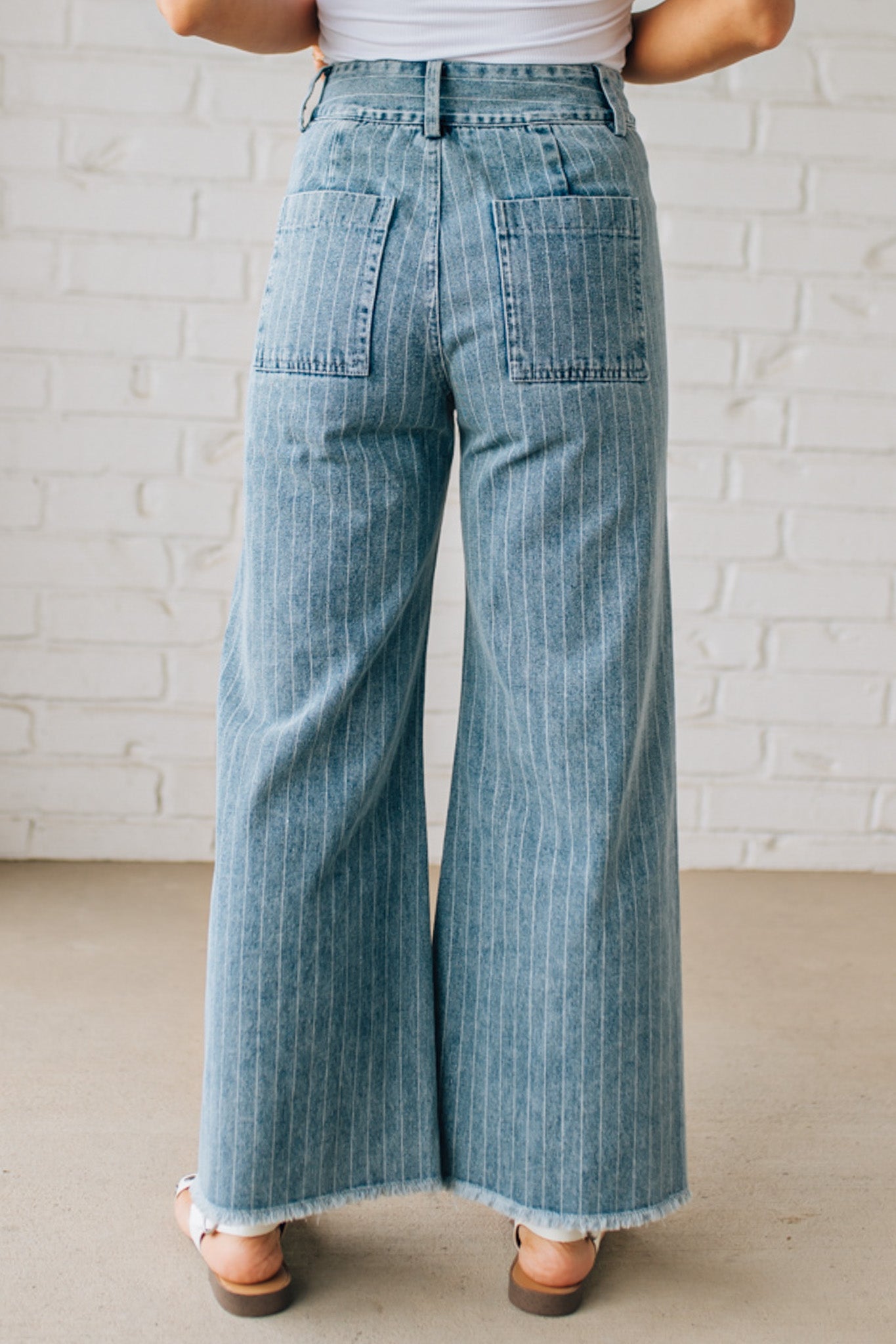 WOMAN WEARING WASHED STRIPE DENIM FRAYED HEM PANTS.