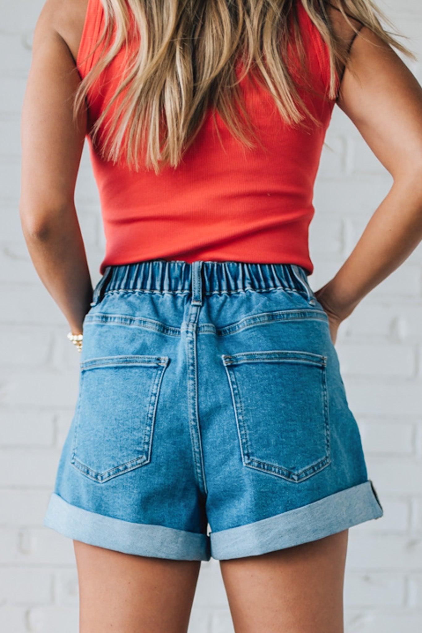 Blonde woman in a red top wearing medium blue Comfort Stretch Loose Fit Denim Shorts.