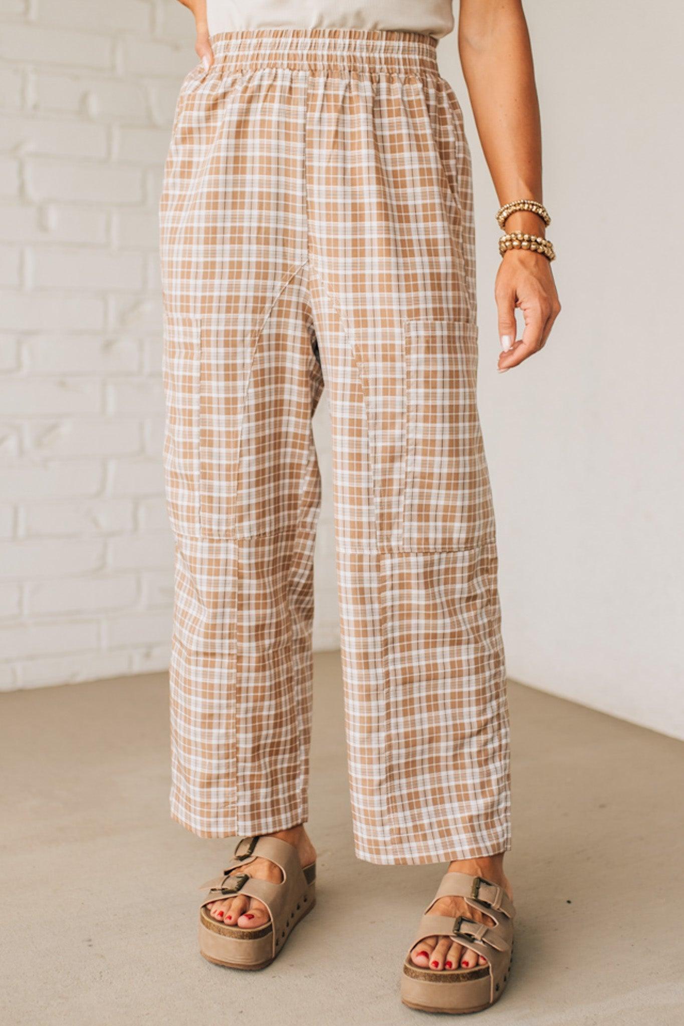 WOMAN WEARING A WHITE TEE AND BROWN SANDALS WITH CHECK PLAID WIDE LEG PANTS WITH THAT HAVE BIG PATCH POCKETS AND ELASTICIZED WAIST.