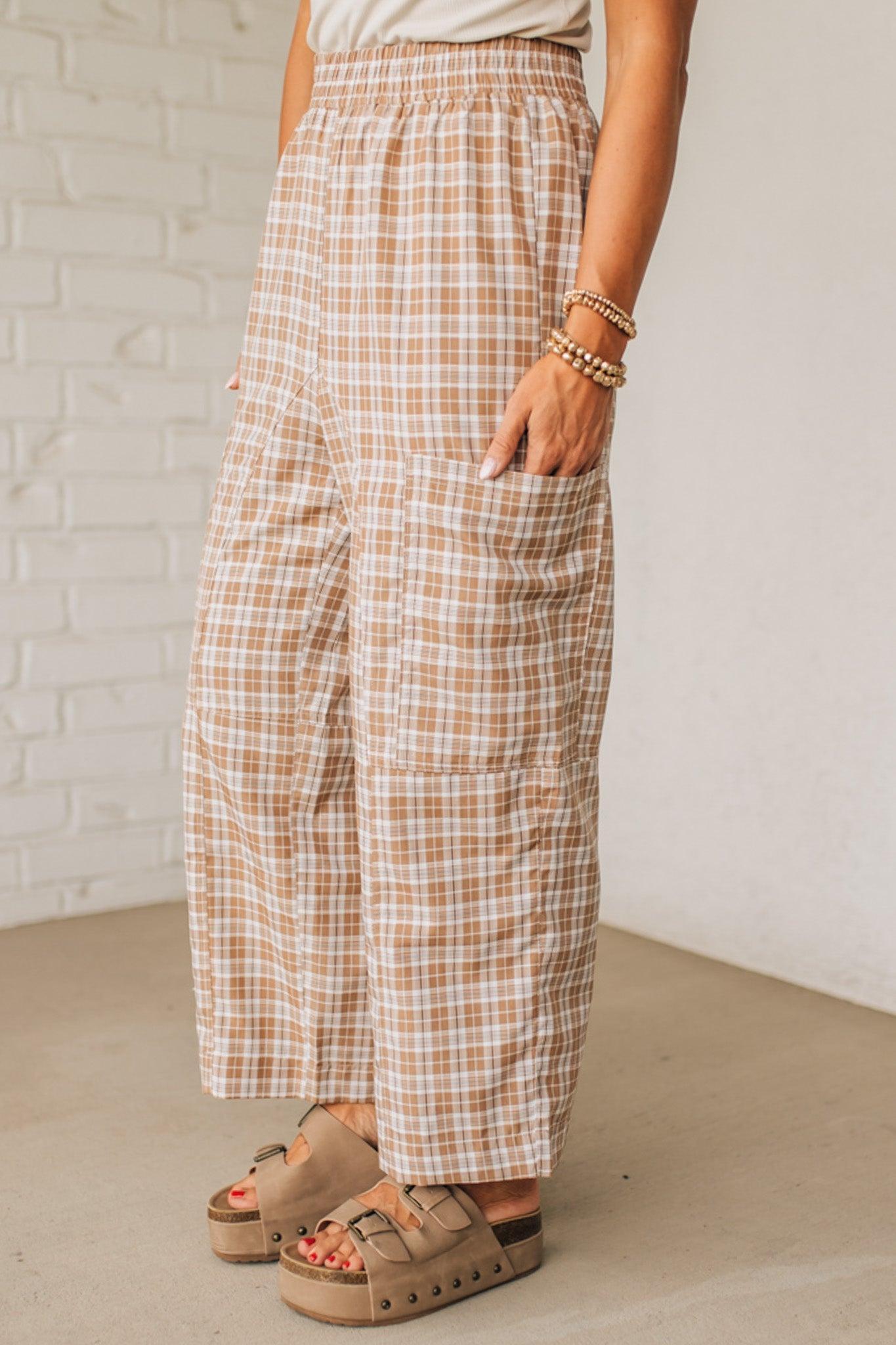 WOMAN WEARING A WHITE TEE AND BROWN SANDALS WITH CHECK PLAID WIDE LEG PANTS WITH THAT HAVE BIG PATCH POCKETS AND ELASTICIZED WAIST.