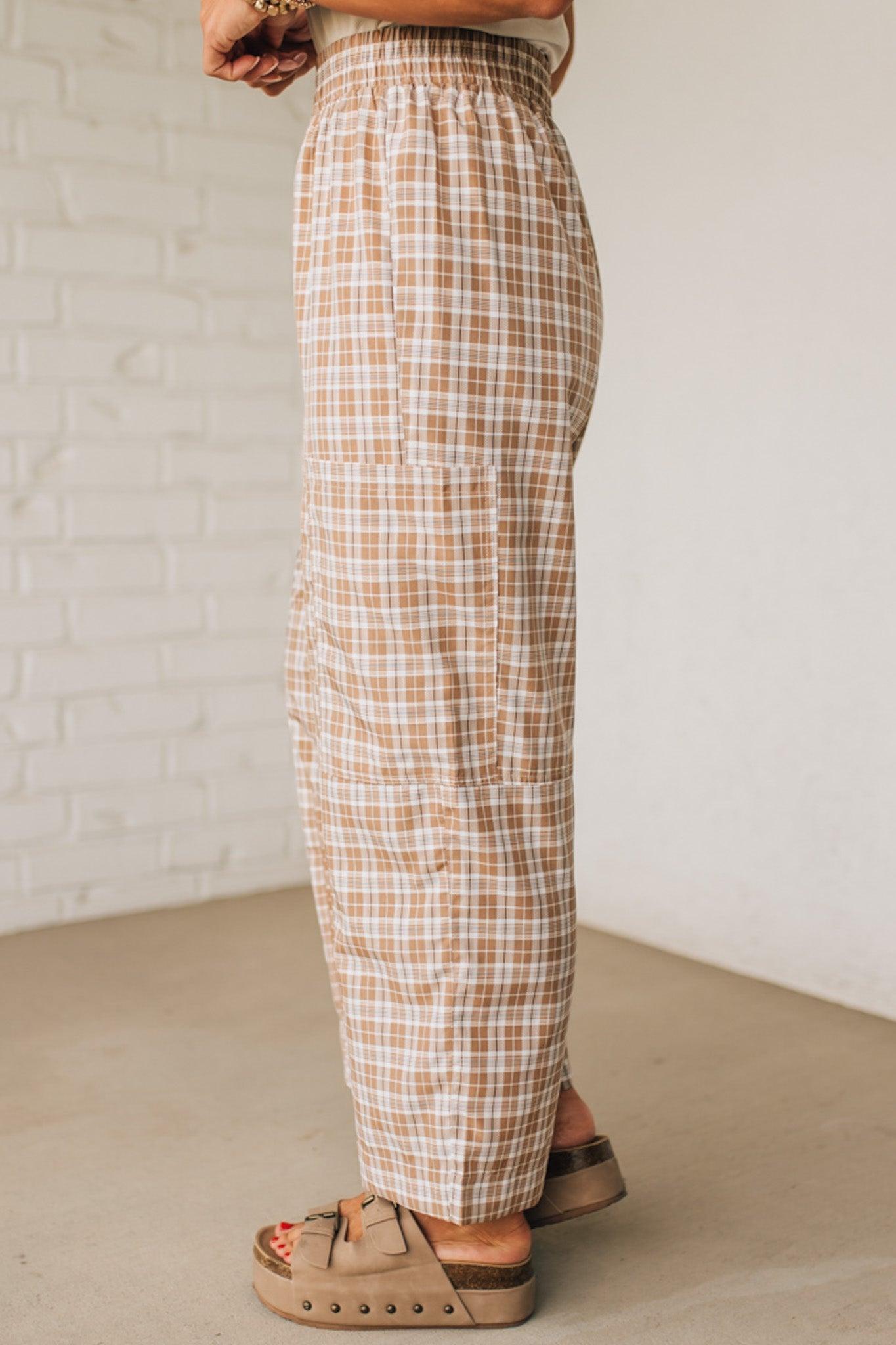 WOMAN WEARING A WHITE TEE AND BROWN SANDALS WITH CHECK PLAID WIDE LEG PANTS WITH THAT HAVE BIG PATCH POCKETS AND ELASTICIZED WAIST.