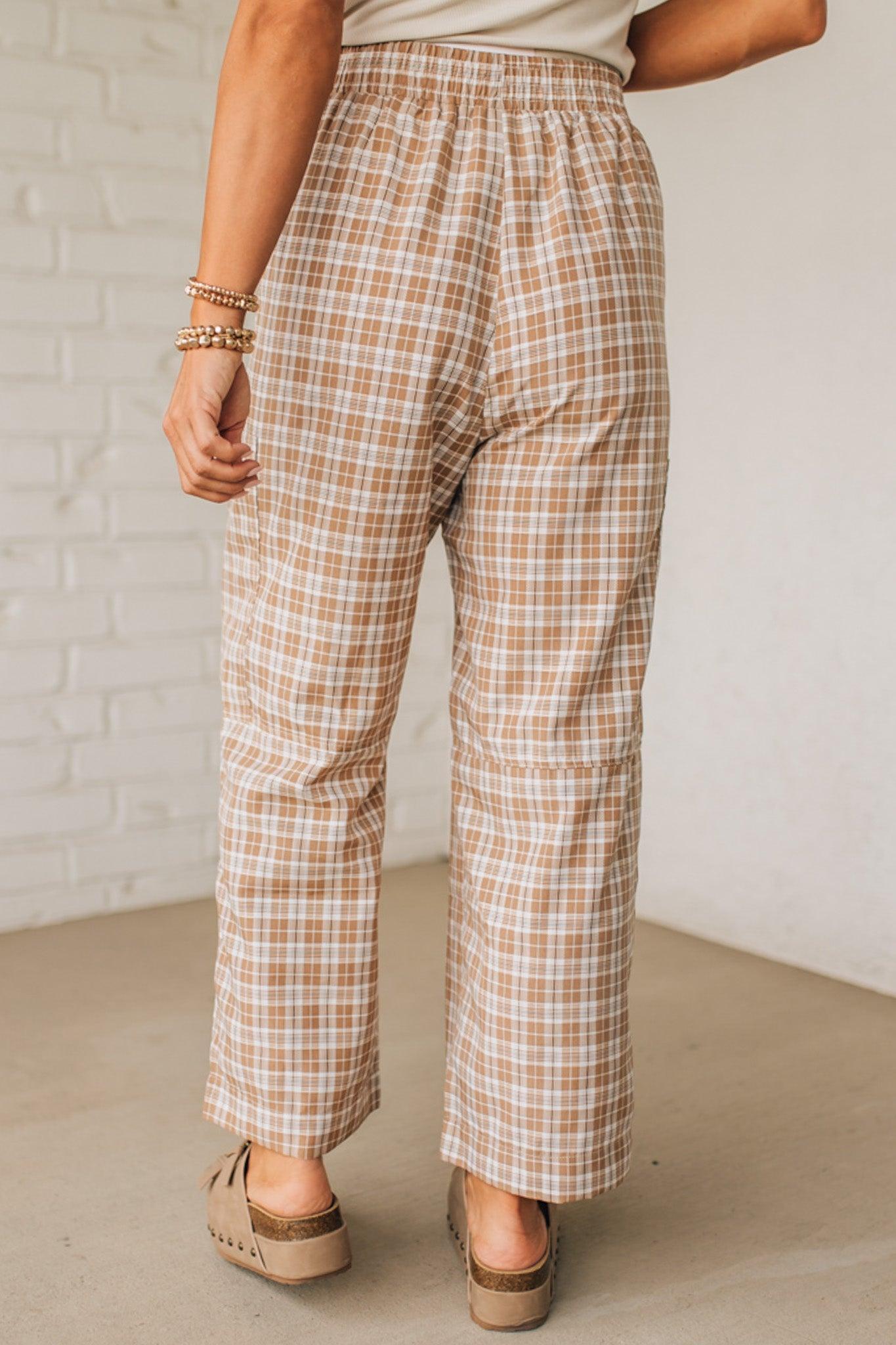 WOMAN WEARING A WHITE TEE AND BROWN SANDALS WITH CHECK PLAID WIDE LEG PANTS WITH THAT HAVE BIG PATCH POCKETS AND ELASTICIZED WAIST.