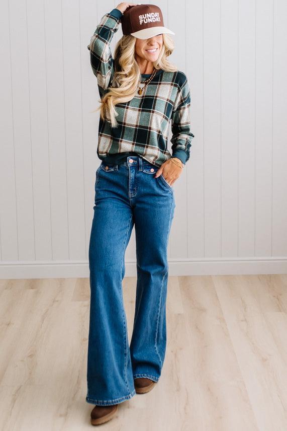 BLONDE WOMAN IN A BROWN HAT WEARING A GREEN CREW NECK, LONG SLEEVE, PLAID PRINTED HACCI TOP