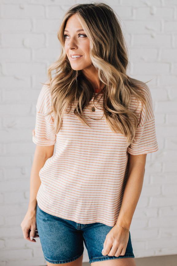 BLONDE WOMAN WEARING A COLOR TRIMMED ROUND NECK, ROLL UP SHORT SLEEVE, POINTELLE STRIPE TOP.