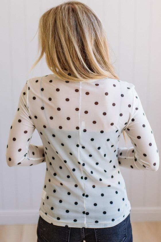 Person wearing a polka dot blouse with a neutral background