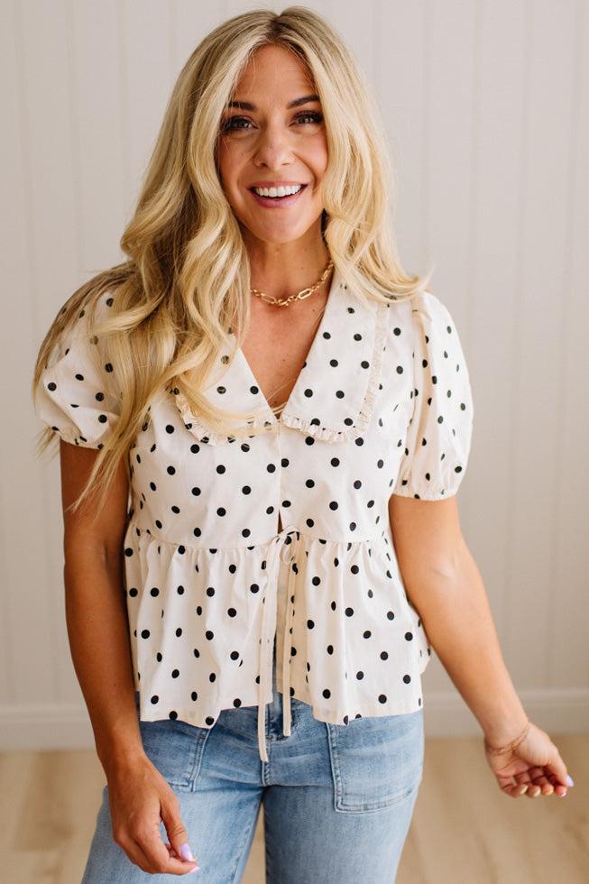 Blonde woman wearing a ivory and black Polka Dot Woven Peter Pan Collar Top with double tie front.