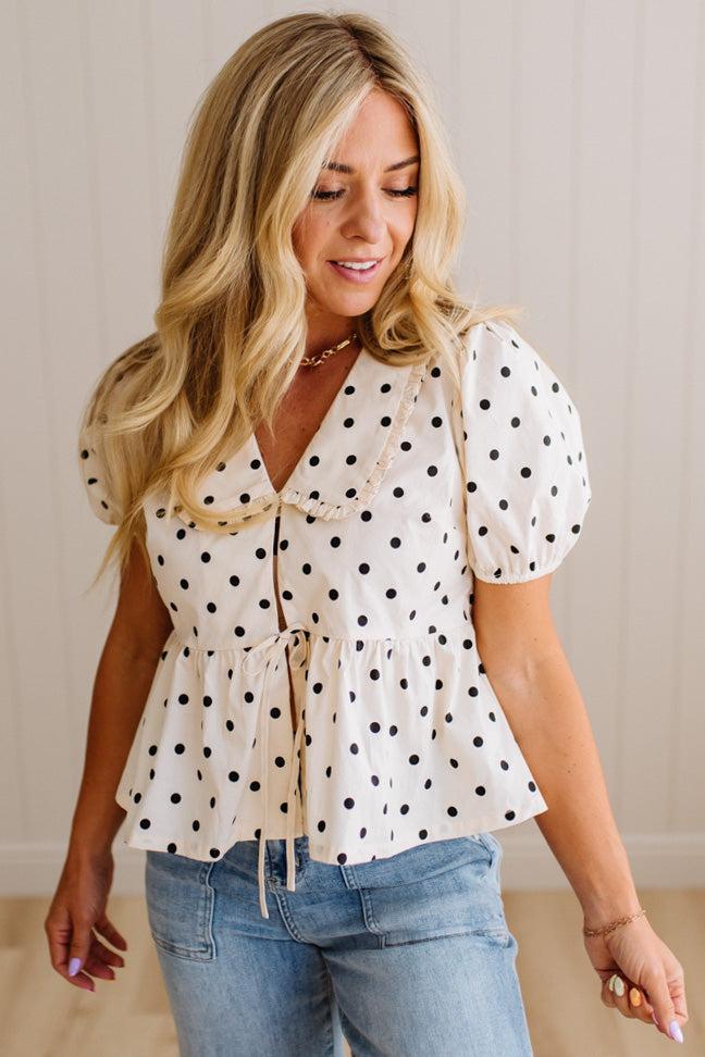 Blonde woman wearing a ivory and black Polka Dot Woven Peter Pan Collar Top with double tie front.