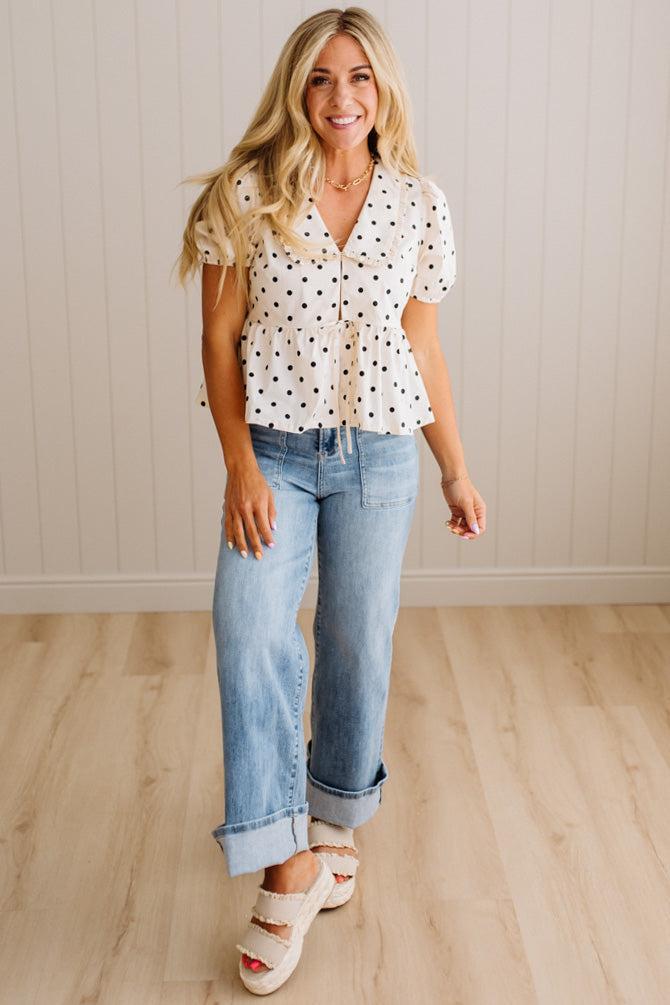 Blonde woman wearing a ivory and black Polka Dot Woven Peter Pan Collar Top with double tie front.