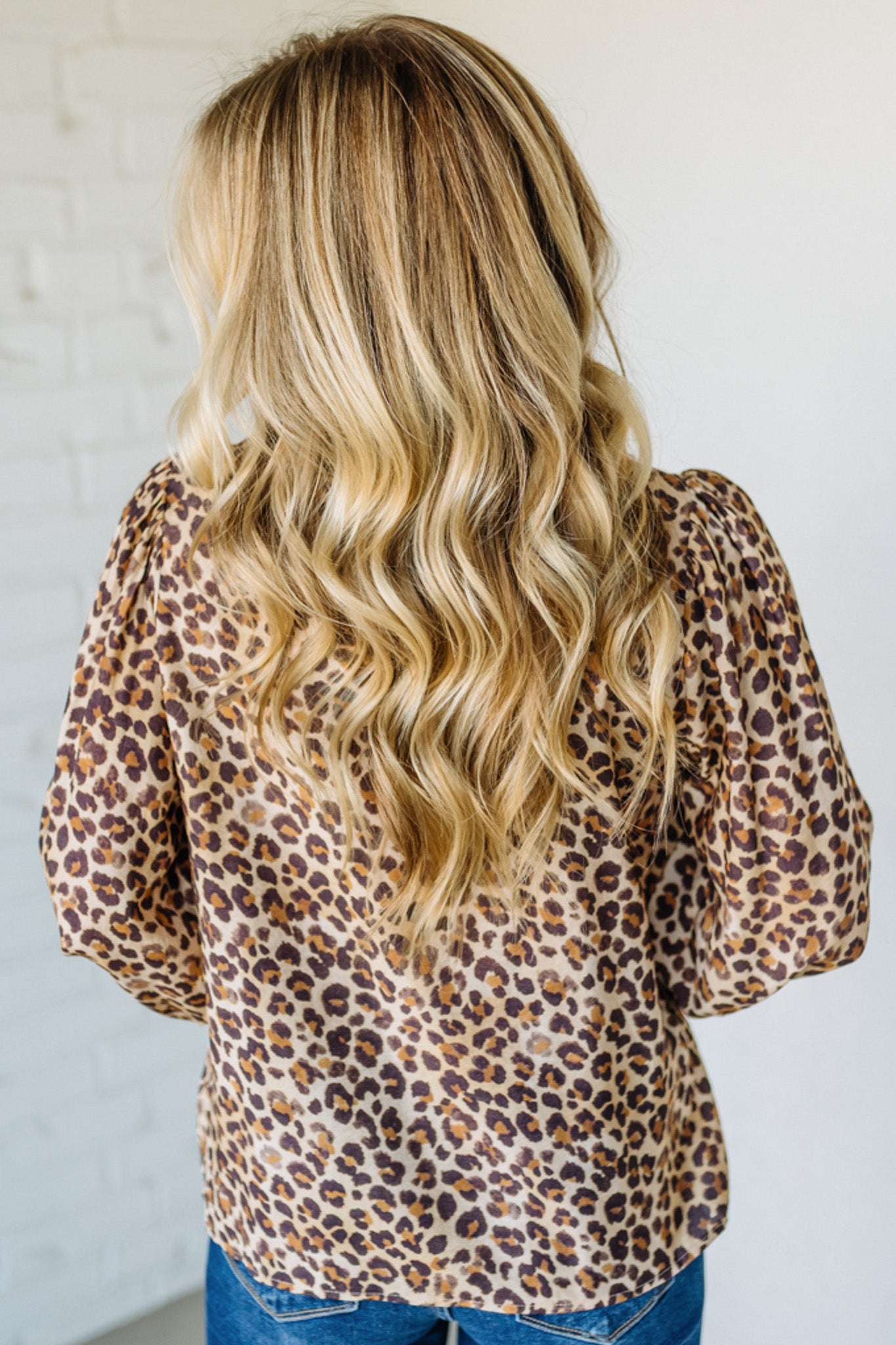 Person wearing a leopard print top with long blonde hair against a white background