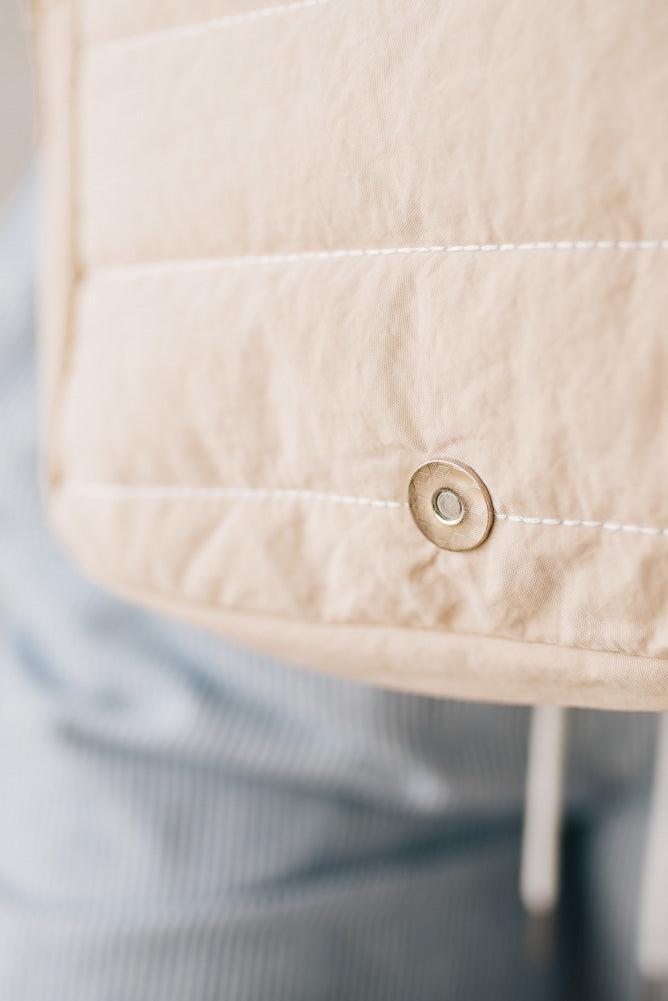 Blonde woman wearing a Foldover Quilted Crossbody bag in stone color.