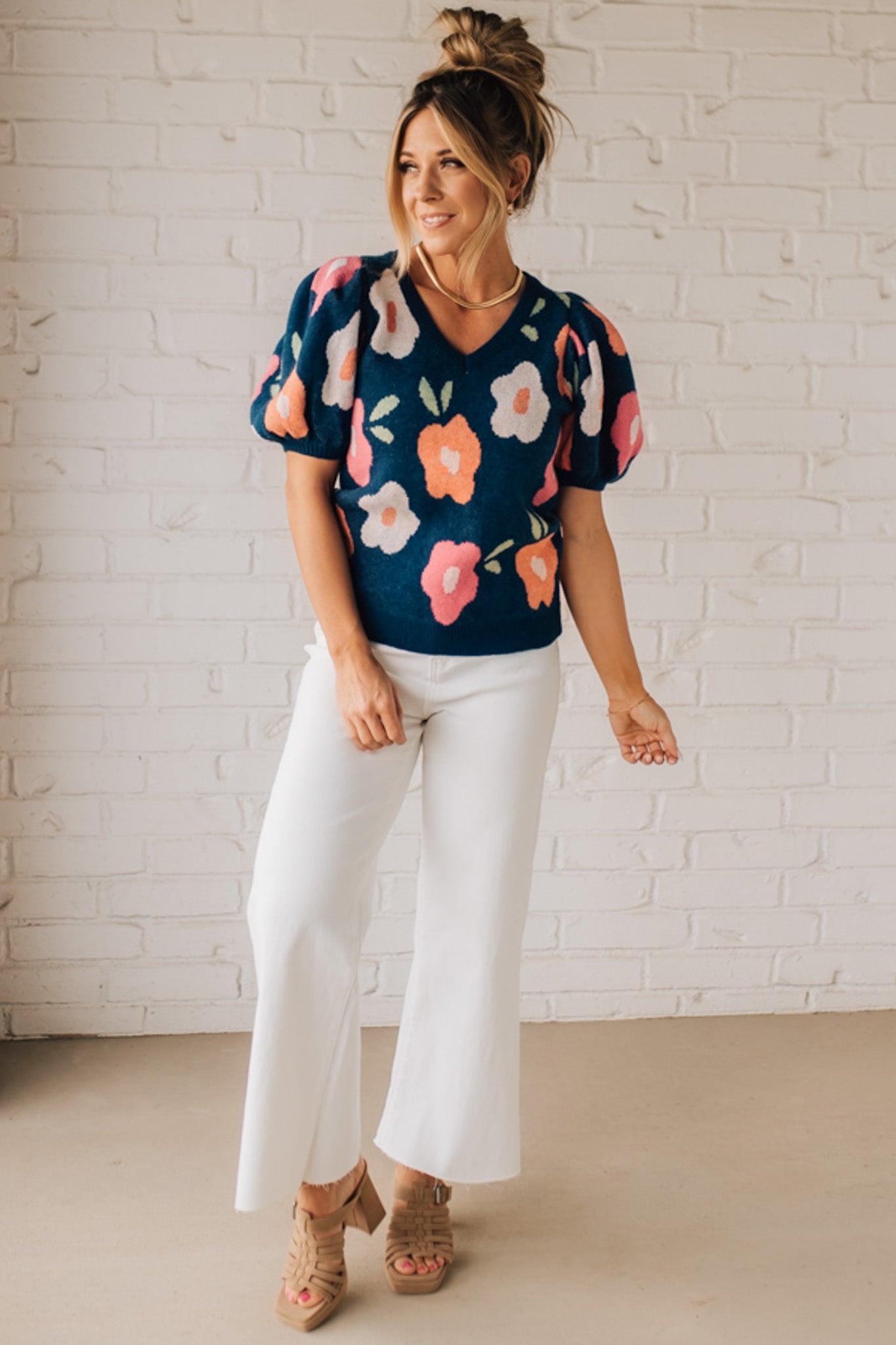 BLONDE WOMAN WEARING A FLORAL PATTERN PUFF SLEEVE SWEATER WITH V-NECK.