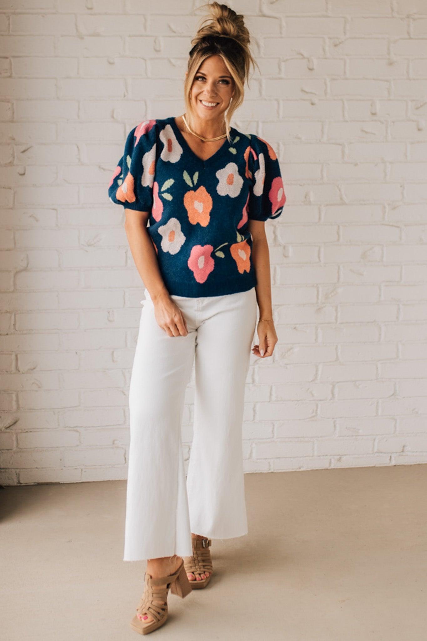 BLONDE WOMAN WEARING A FLORAL PATTERN PUFF SLEEVE SWEATER WITH V-NECK.