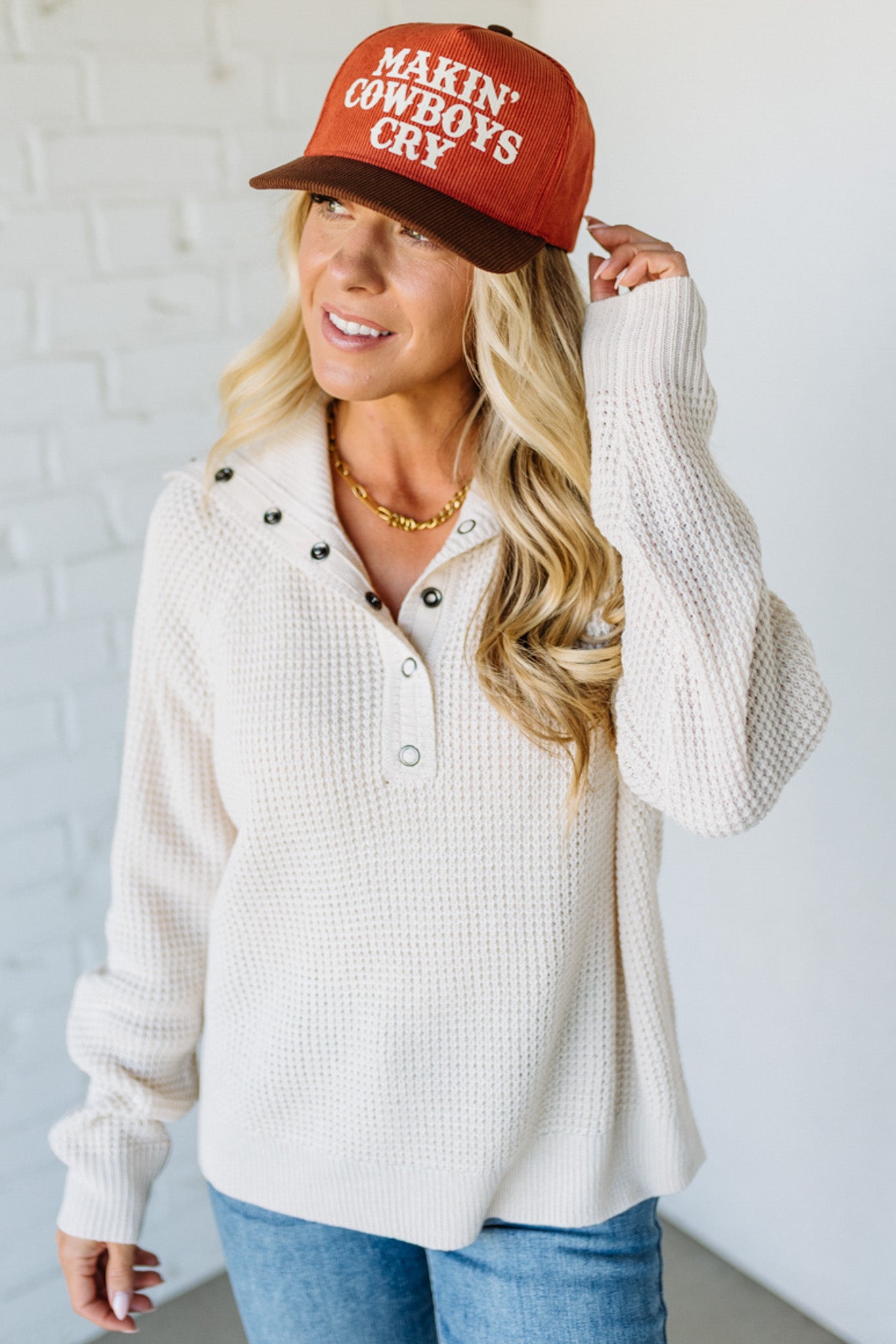 Woman wearing a red cap with text and a white sweater against a light background