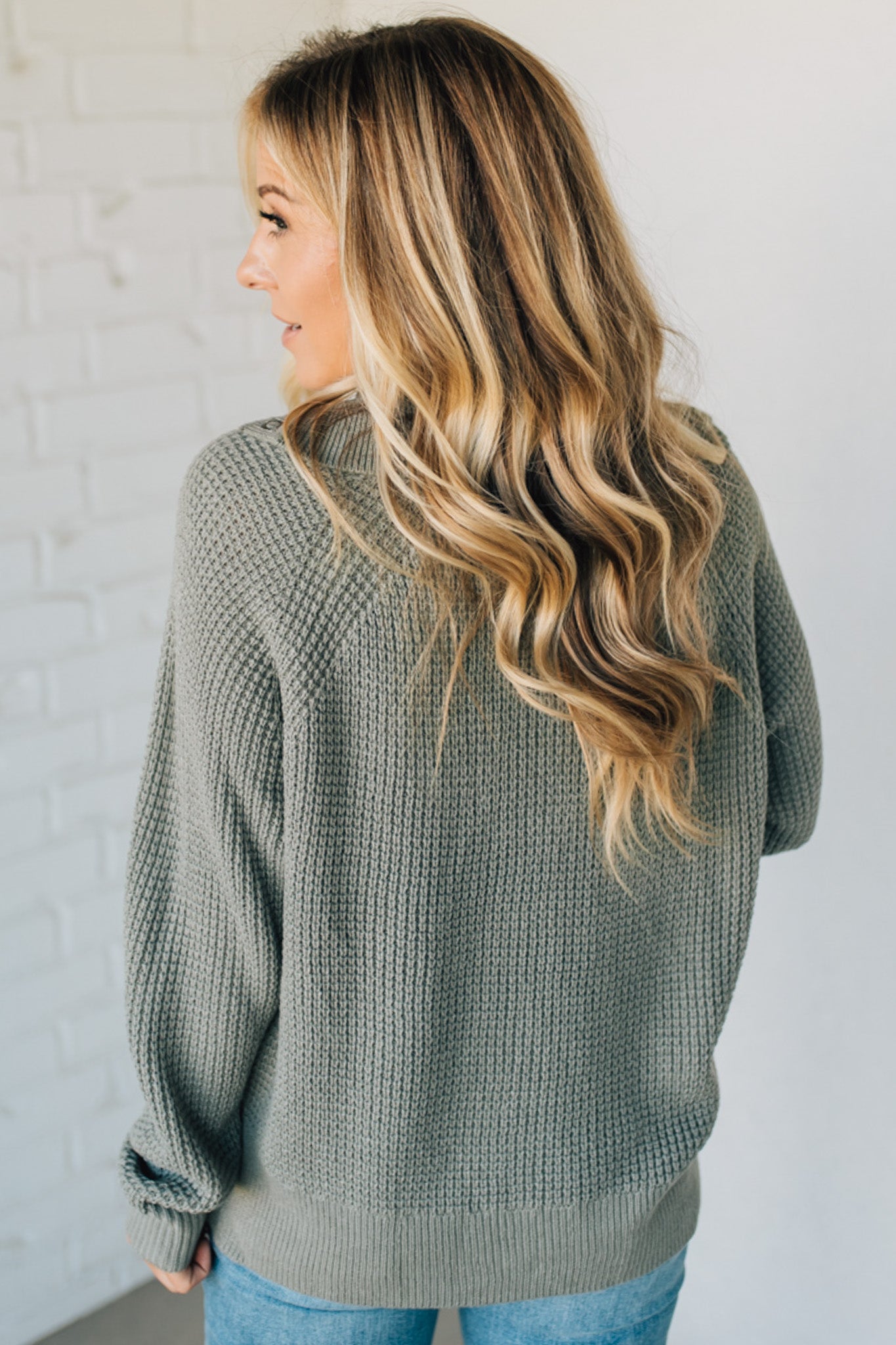 Woman wearing a green sweater against a white wall