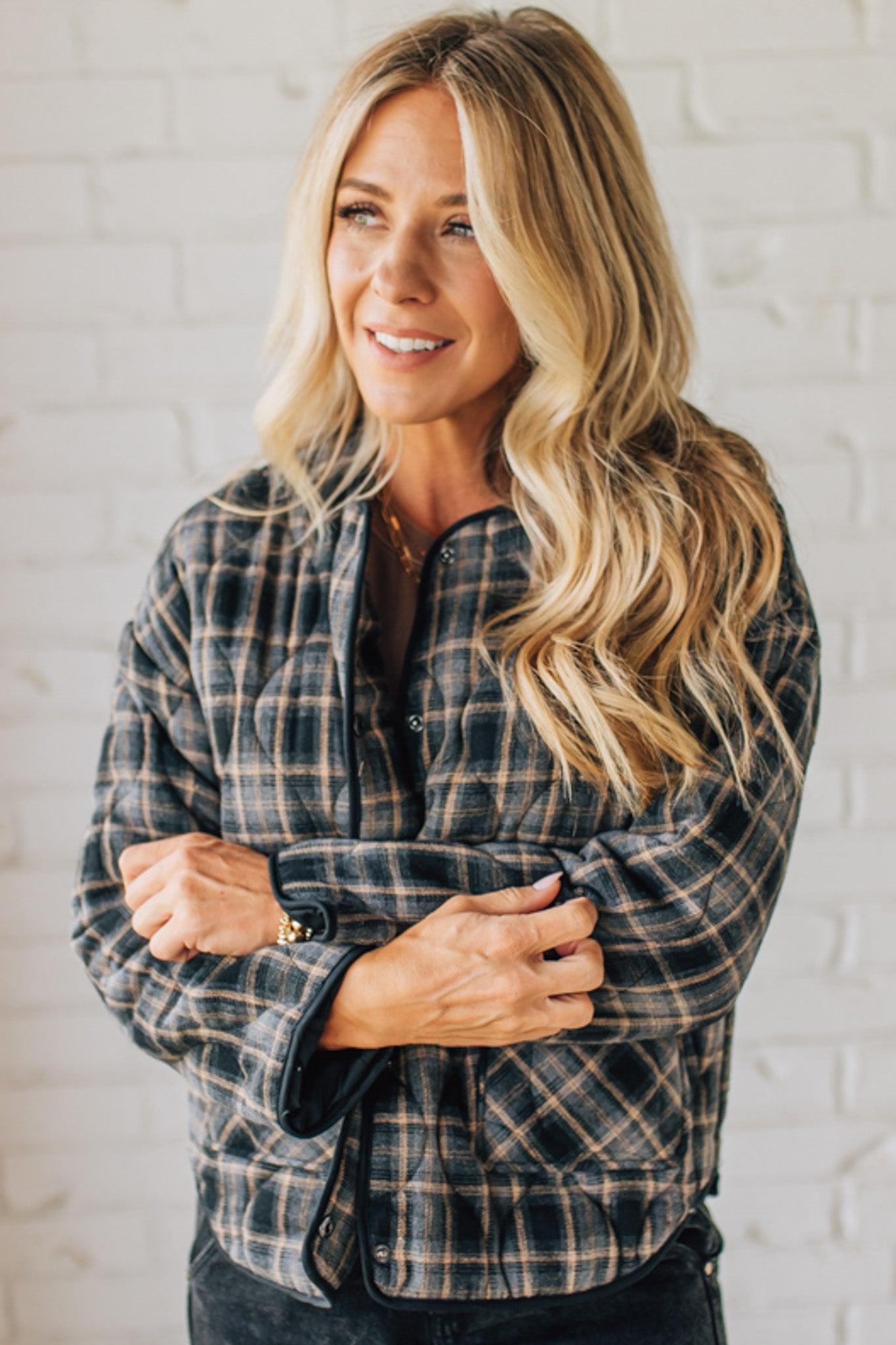 Woman wearing a plaid shirt against a white brick wall