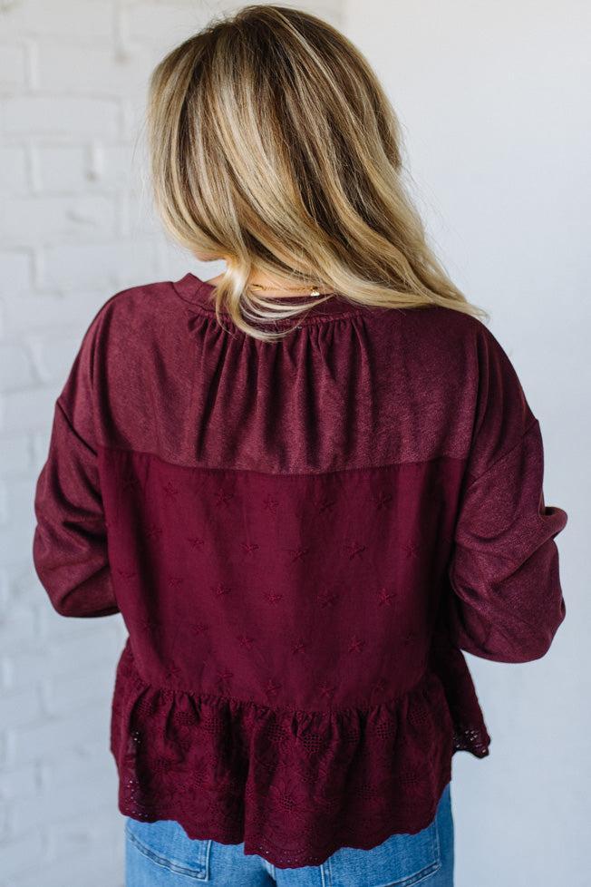 Blonde woman wearing a wine colors sweatshirt with peplem hem in eyelet lace.