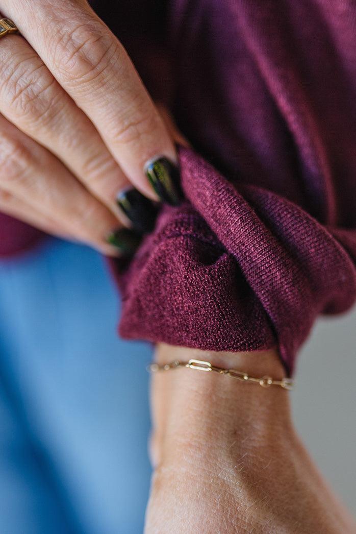 Close-up of a hand wearing a burgundy sleeve with a blurred background