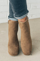 Person wearing brown ankle boots with block heel and smooth faux suede finish.