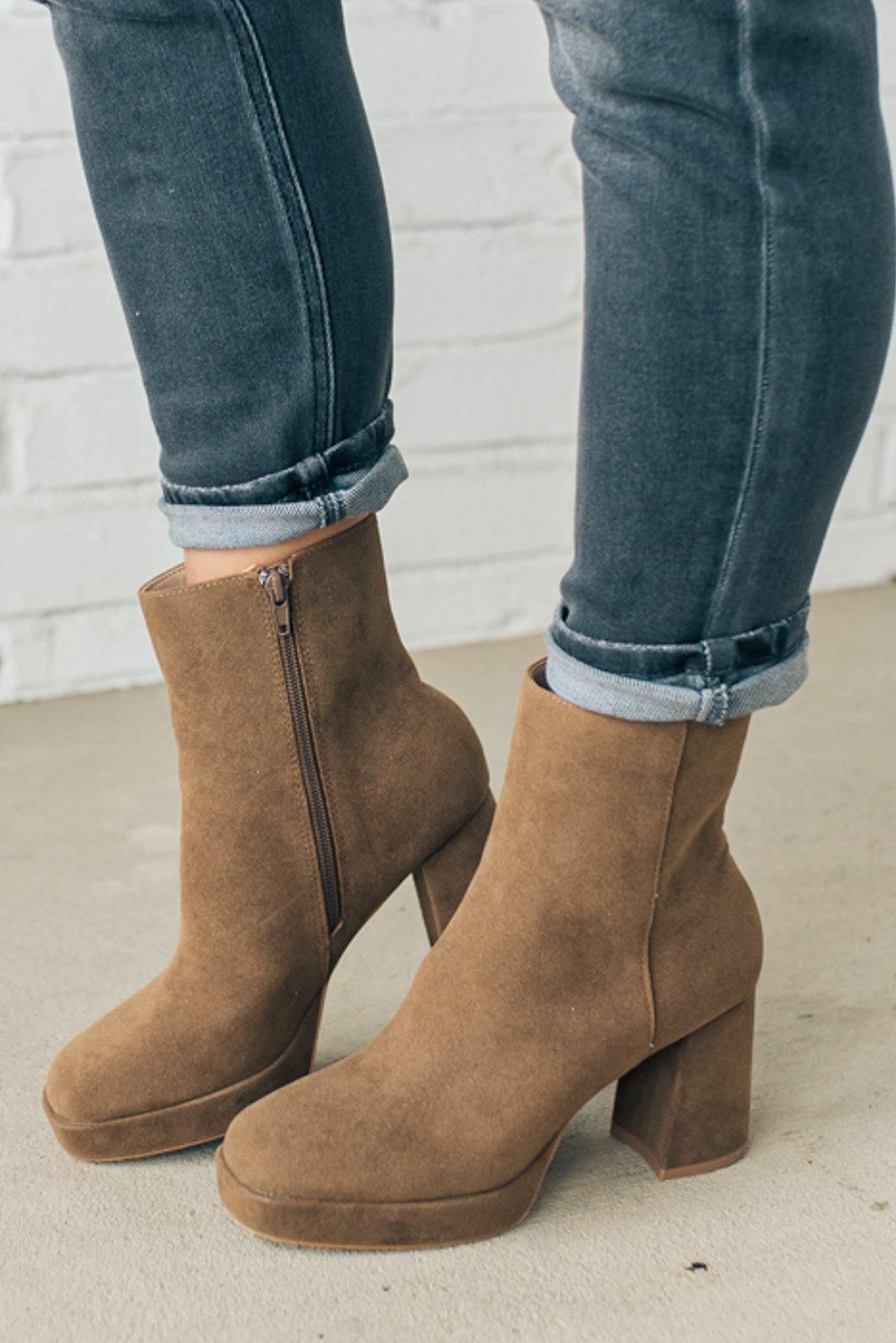 Person wearing brown ankle boots with block heel and smooth faux suede finish.