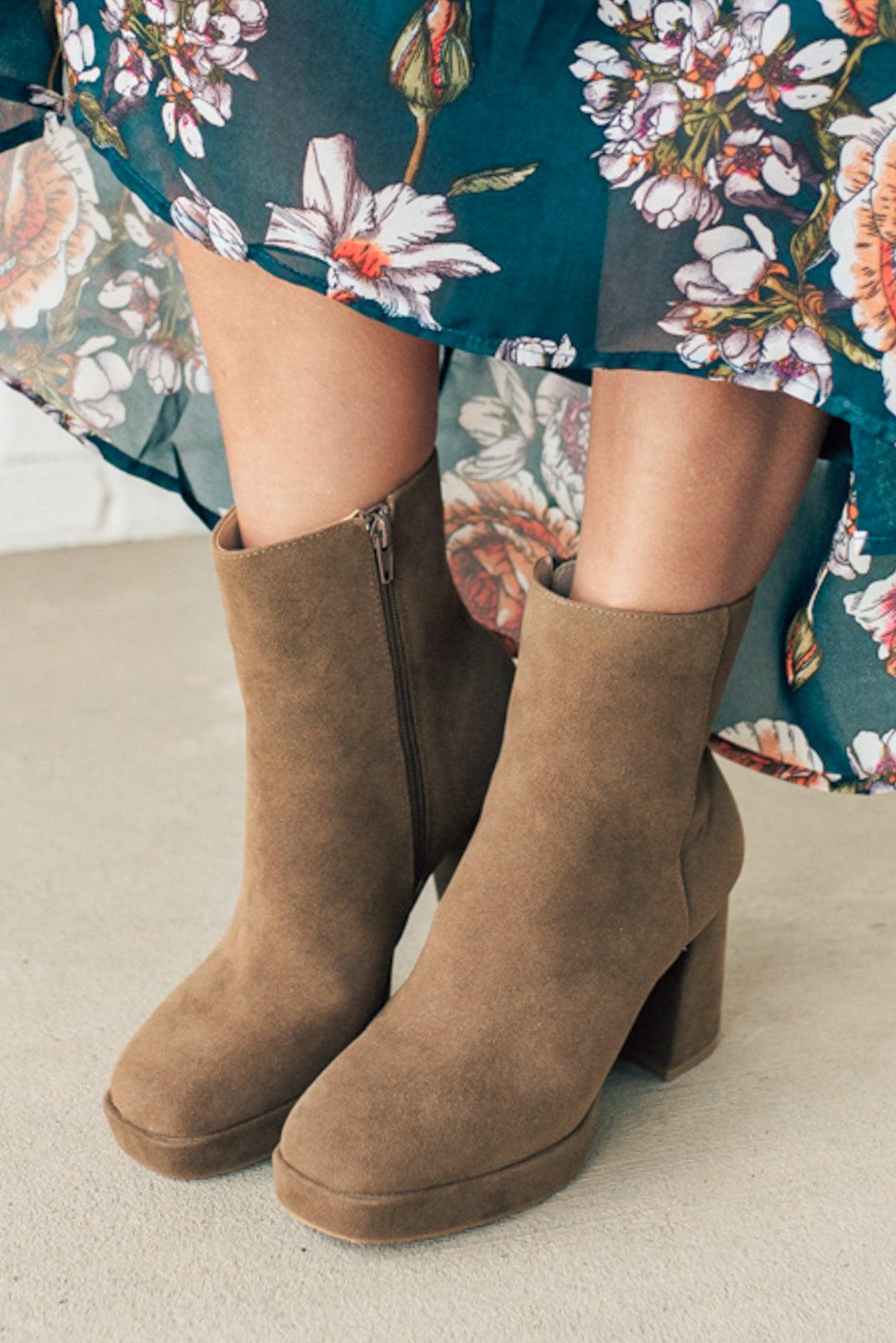 Person wearing brown ankle boots with block heel and smooth faux suede finish.