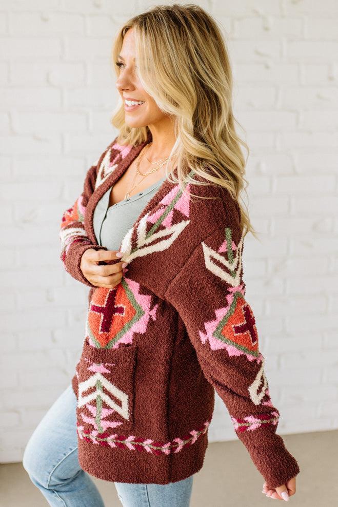 Woman wearing a patterned cardigan with a white brick wall background