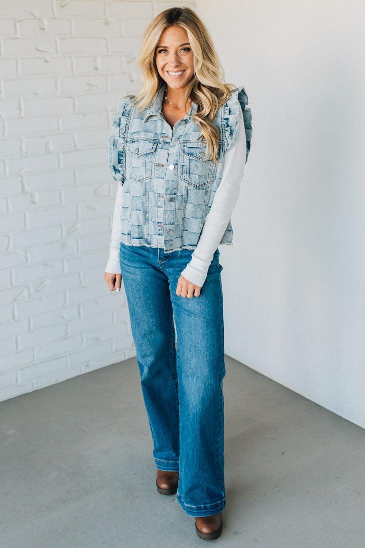 Woman wearing a denim checkered vest over a white shirt against a plain background