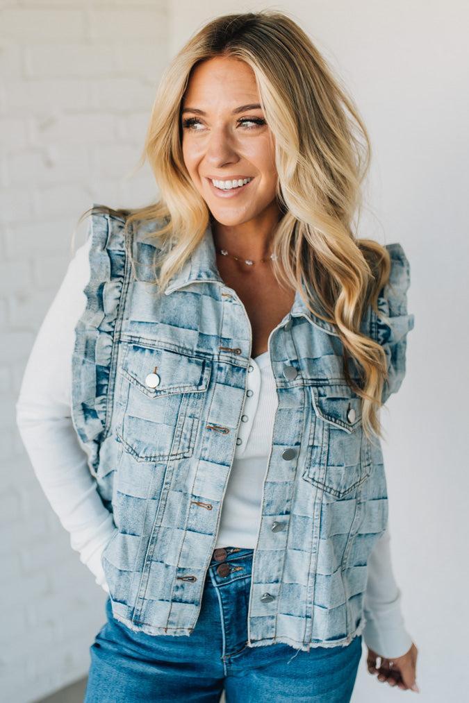 Woman wearing a denim checkered vest over a white shirt against a plain background