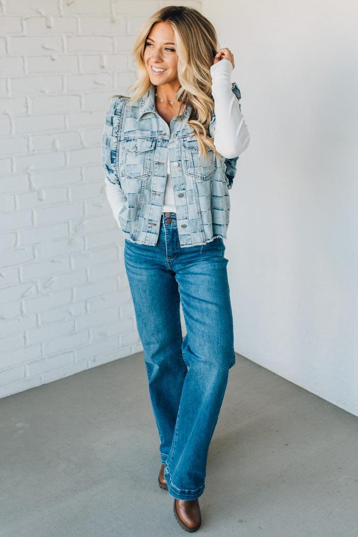 Woman wearing a denim checkered vest over a white shirt against a plain background