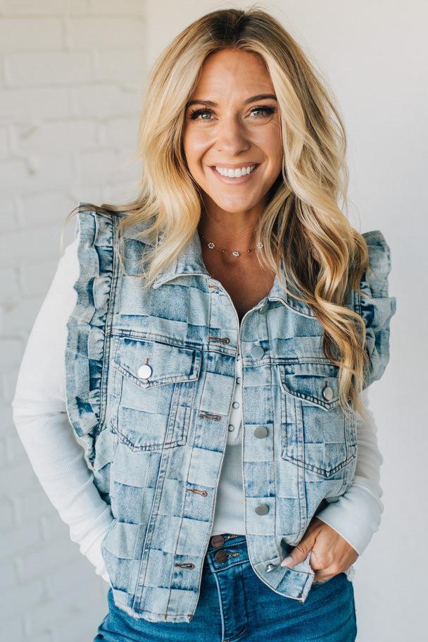 Woman wearing a denim checkered vest over a white shirt against a plain background
