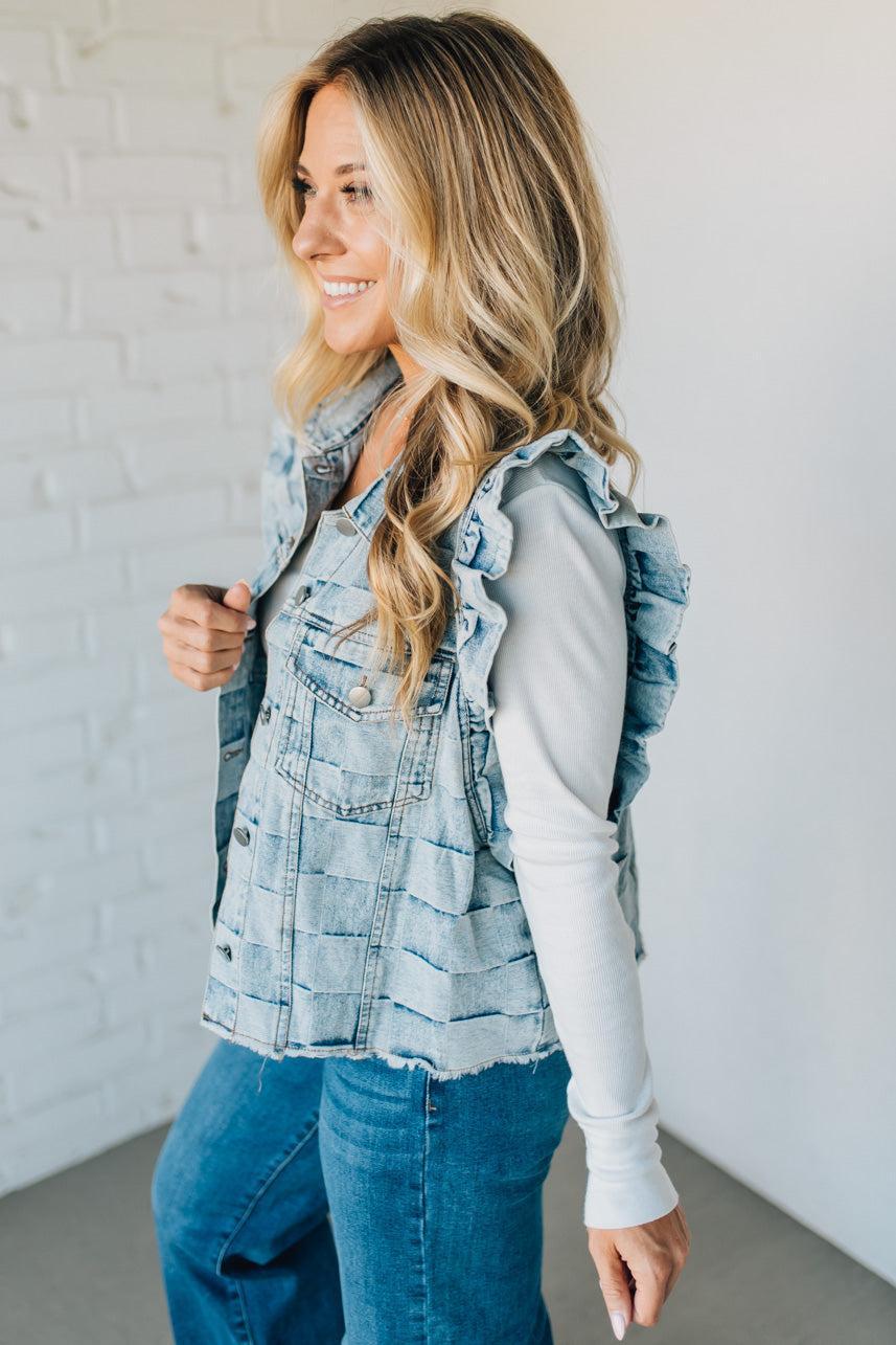 Woman wearing a denim checkered vest over a white shirt against a plain background